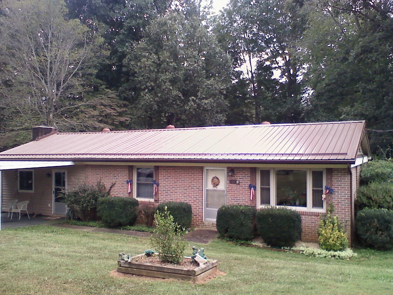 Bronze metal roof on a brick ranch home with a carport in Perkinsville